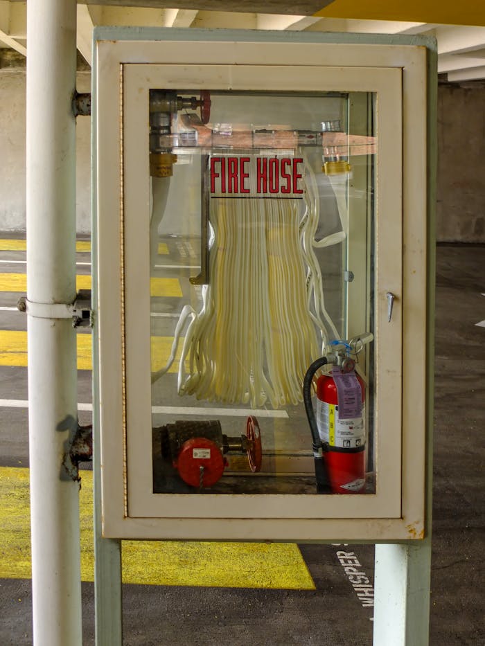why-choose-us Vertical shot of a fire hose and extinguisher in a parking garage, ensuring safety.