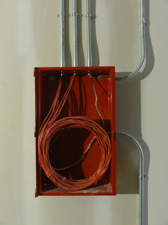 gallery-1 Industrial red electrical box with coiled cables and metal conduit on a wall.