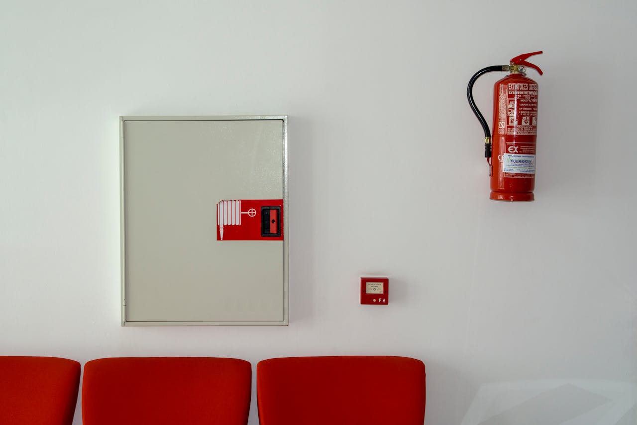 gallery-3 Fire extinguisher and safety equipment mounted on a white wall with red seating below.
